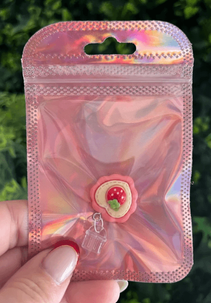 Bouchon poussière en forme de coeur avec une fraise dans son centre